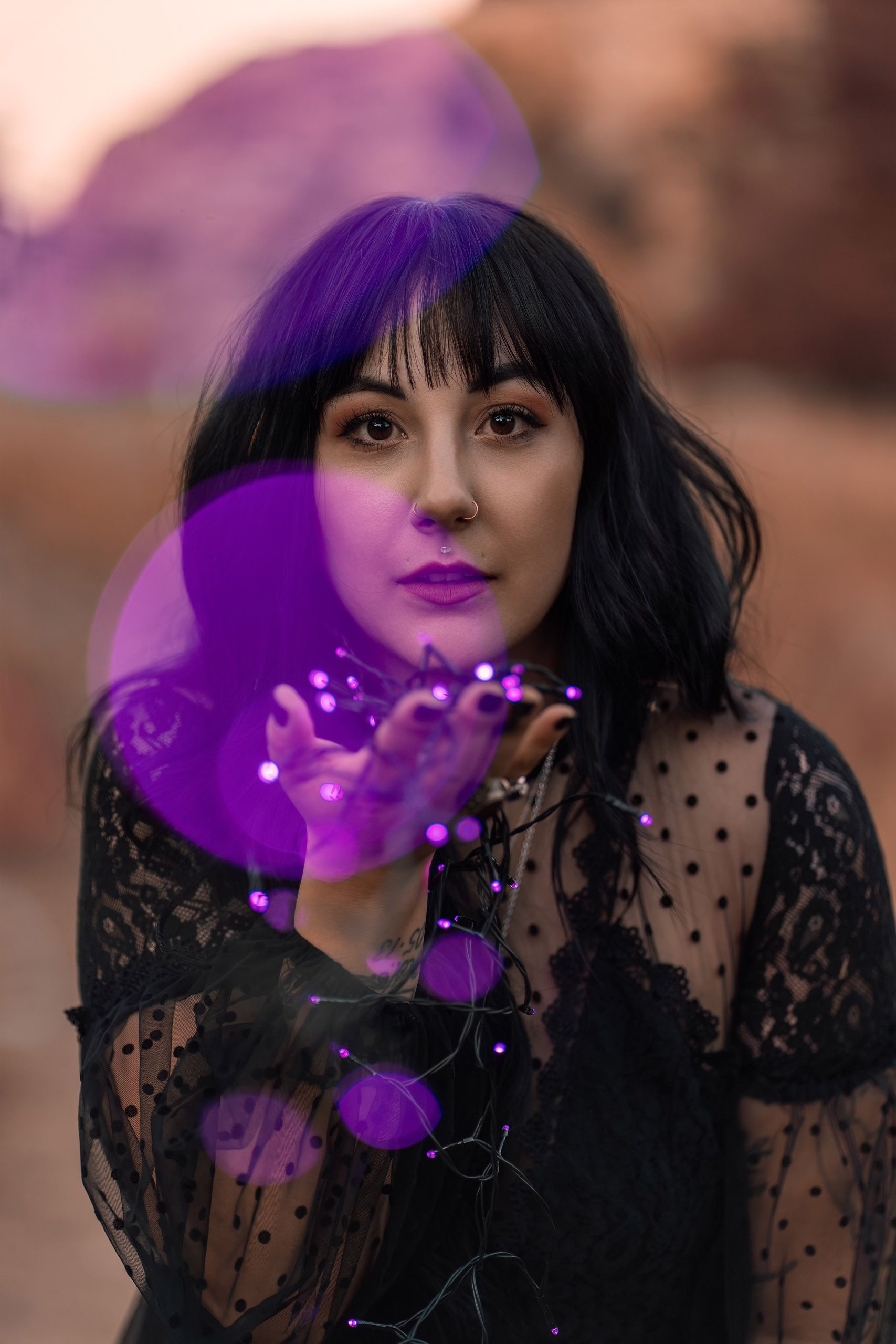 Close-up portrait of a woman holding purple fairy lights with glowing purple bokeh